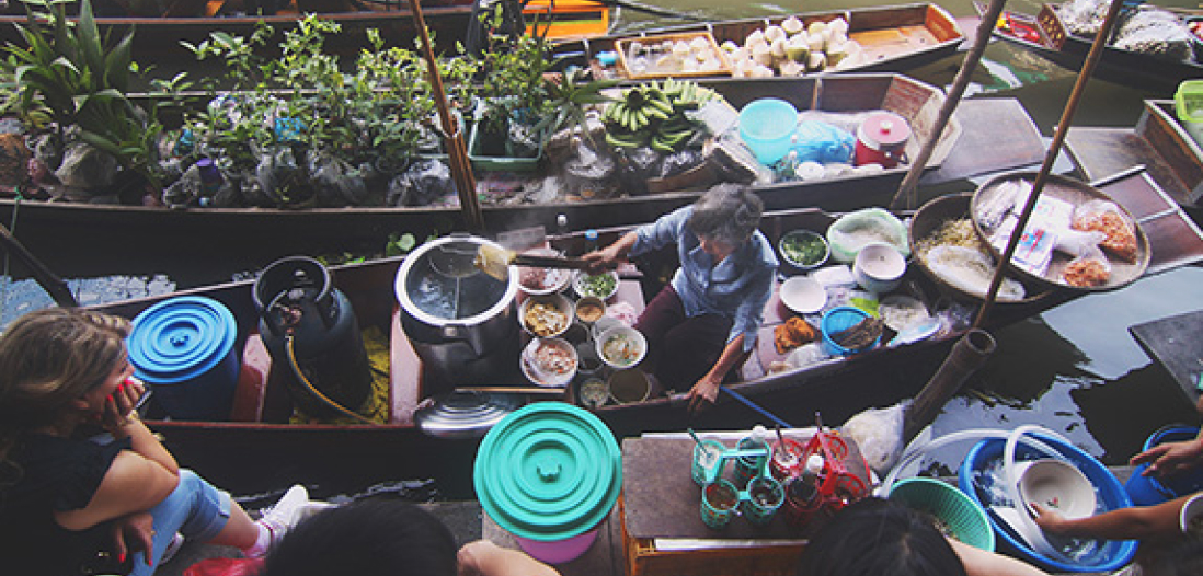 A woman selling food on a longtail boat in an Asian floating market