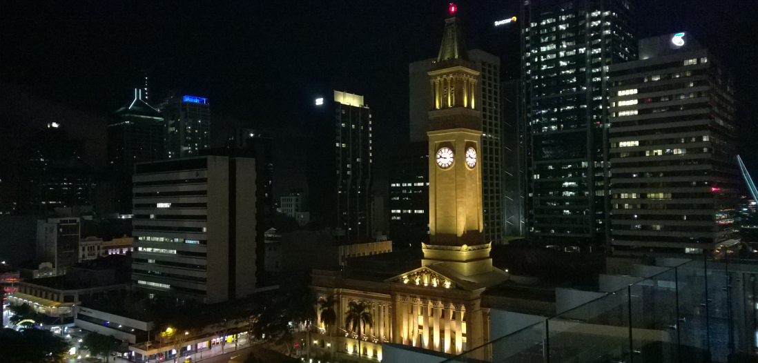 A nighttime cityscape of Brisbane city, overlooking city hall and the clock tower